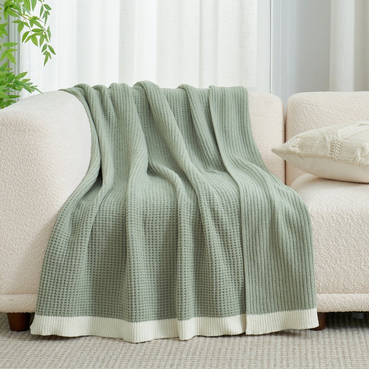 Chenille Waffle Knit Throw Blanket in Sage Green draped over a sofa, showcasing its soft tone and cozy texture. #color_Sage Green