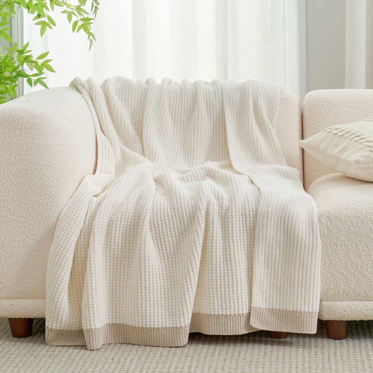 Chenille Waffle Knit Throw Blanket in Ivory draped over a sofa, showcasing its soft neutral tone and texture. #color_Ivory