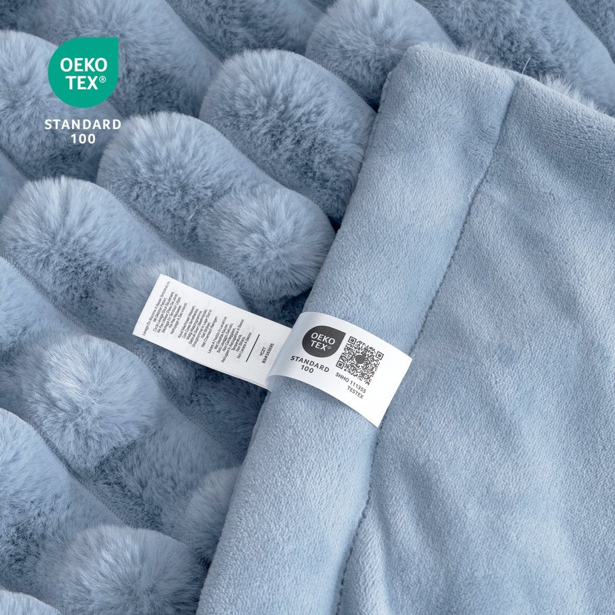 Close-up of Cozy Bliss blue striped faux fur blanket Oeko-Tex certified label, soft and cozy bedding for comfort.. #color_Misty Blue