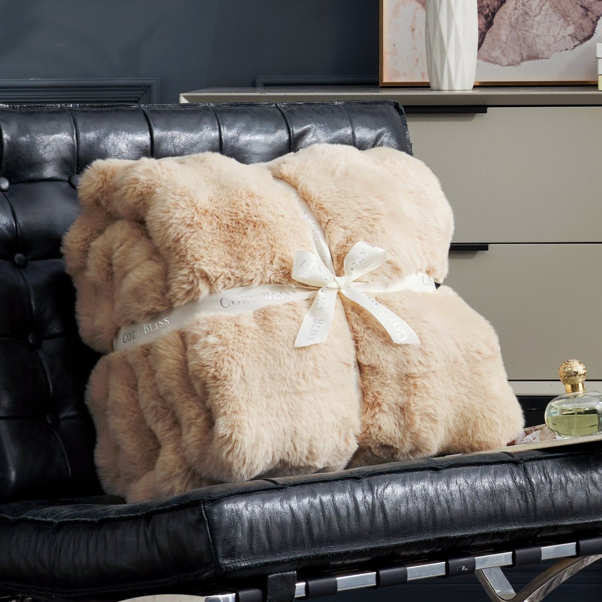 Cozy Bliss beige faux fur throw blanket on black leather chair, perfect for gift. #color_Beige
