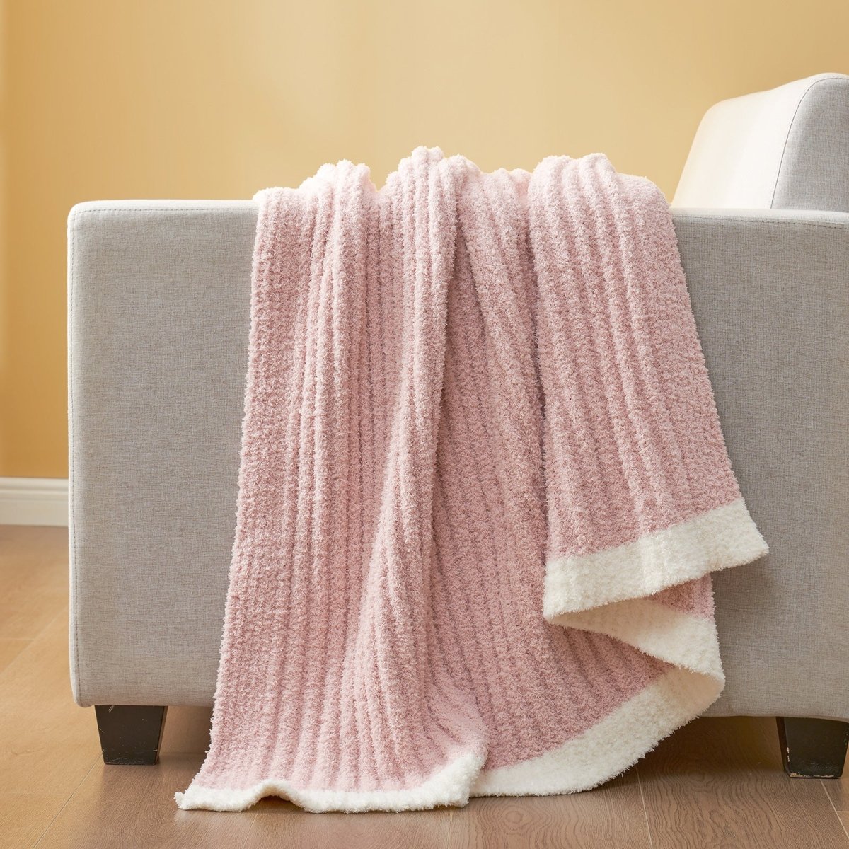 Soft Ribbed Feather Yarn Throw Blanket in Pink draped over the back of a sofa, highlighting soft ribbed texture and cozy fabric feel. #Color_Pink