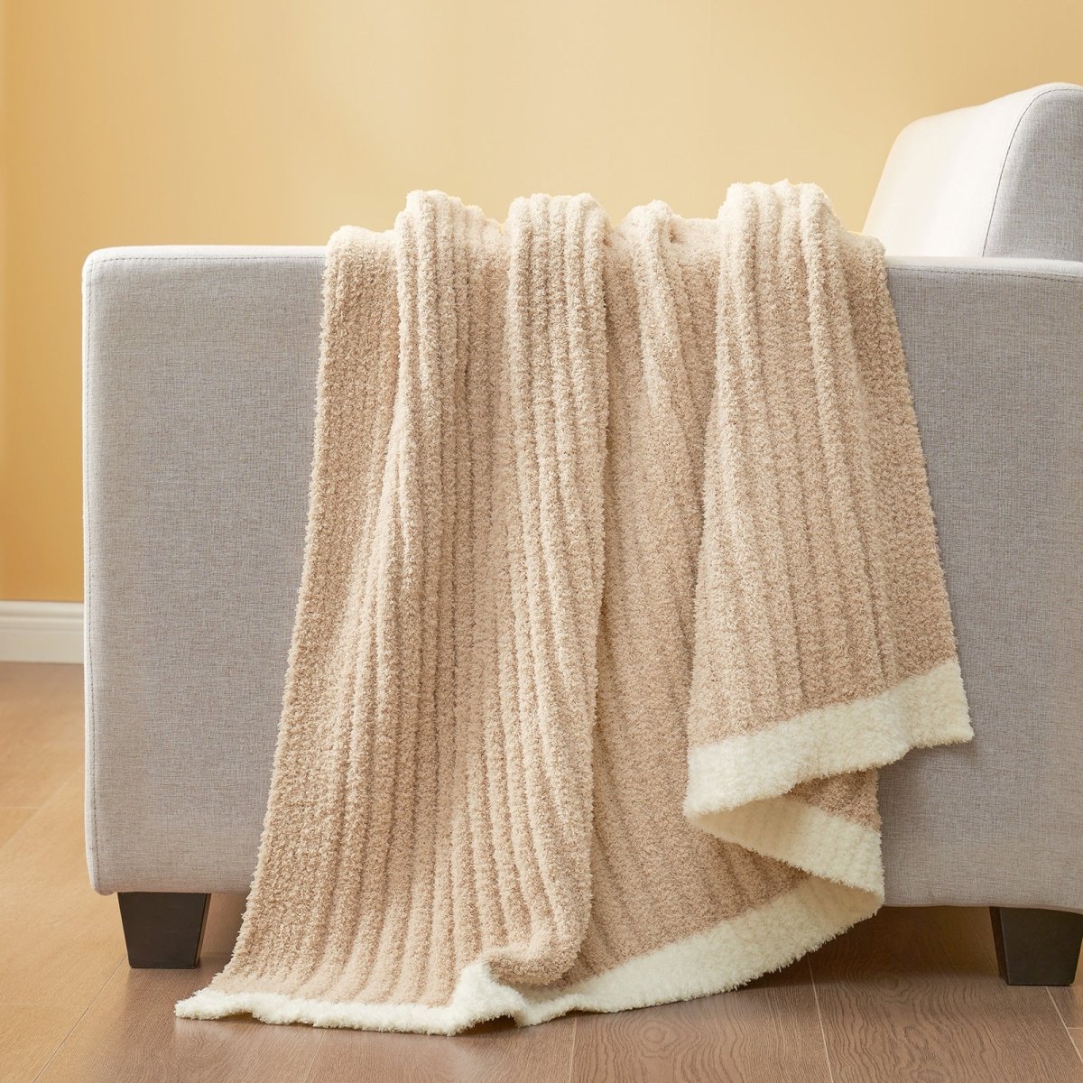 Soft Ribbed Feather Yarn Throw Blanket in Beige draped over the back of a sofa, highlighting soft ribbed texture and cozy fabric feel. #Color_Beige