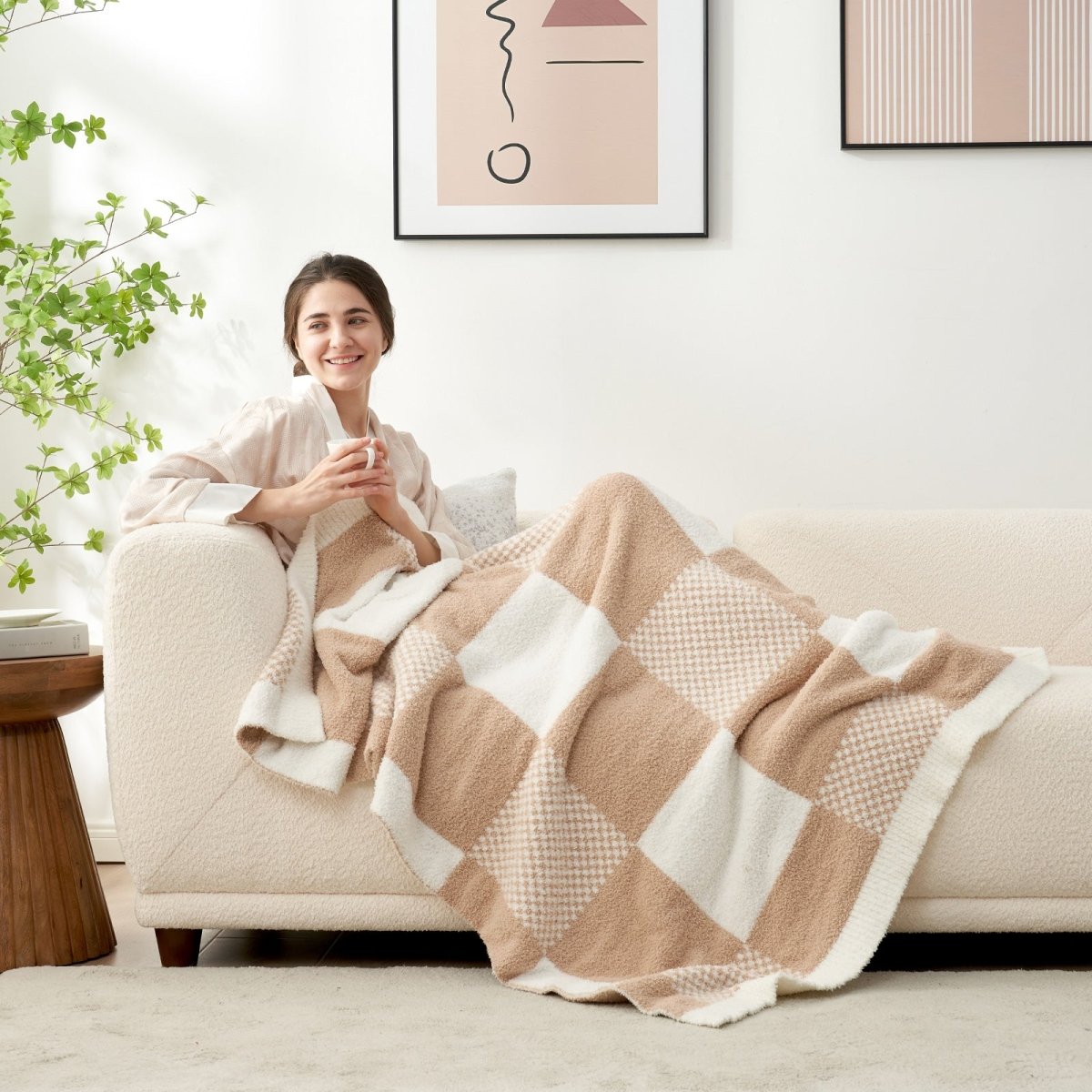 Woman relaxing on a sofa while using Checkered Feather Yarn Throw Blanket in Beige & White in a cozy room setting. #color_Beige & White