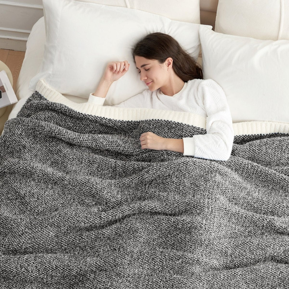Woman sleeping under a Heather Feather Yarn Throw Blanket in Black, offering warmth. #color_Black