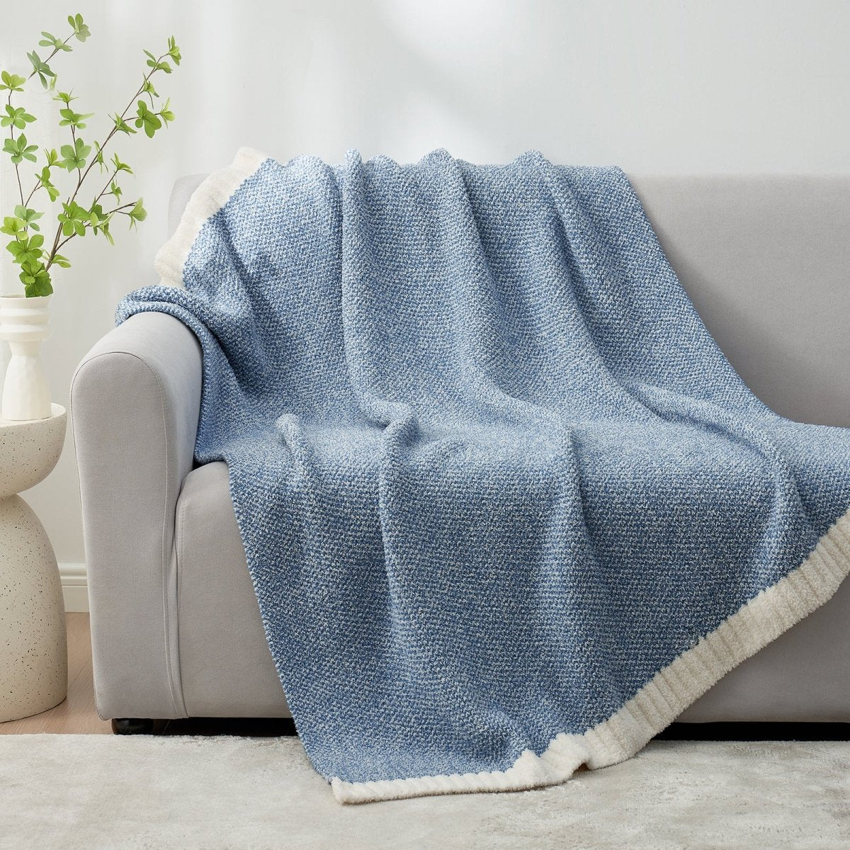 Heather Feather Yarn Throw Blanket in misty blue draped over a sofa, adding warmth, softness and a modern cozy touch to your living room. #Color_Misty Blue