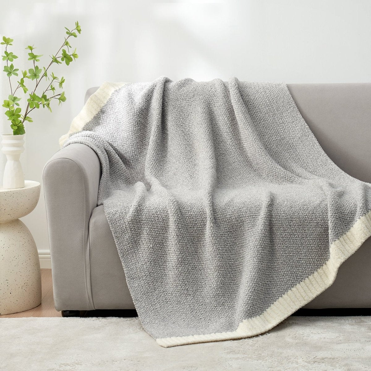 Heather Feather Yarn Throw Blanket in Grey draped over a sofa, adding warmth, softness and a modern cozy touch to your living room. #Color_Grey