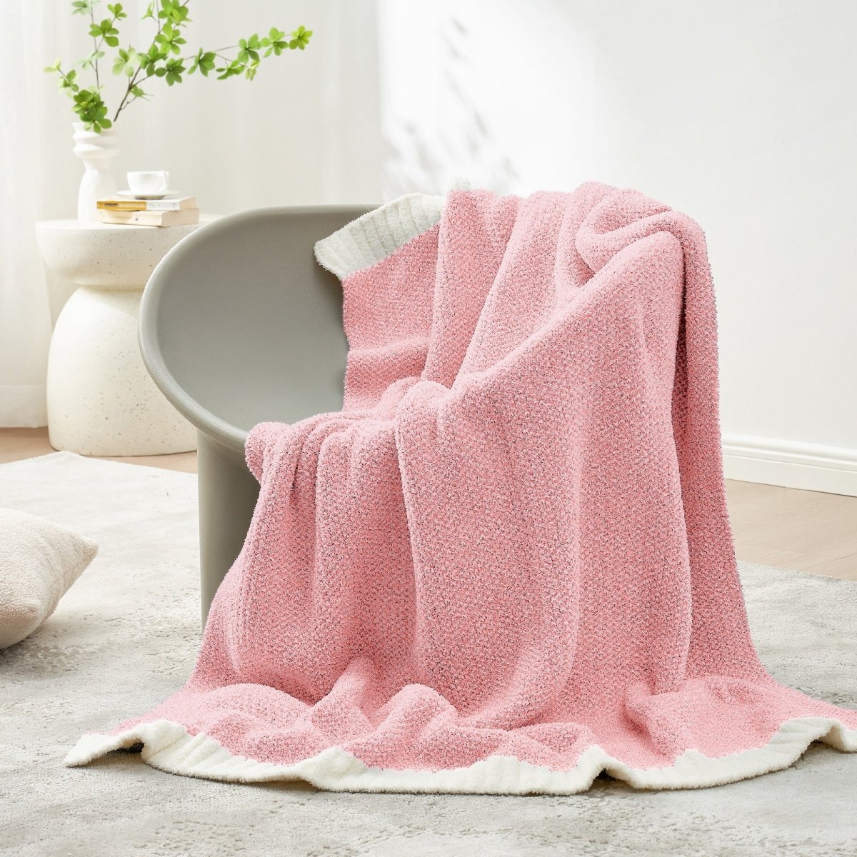 Heather Feather Yarn Throw Blanket in Pink draped over a chair, adding a soft cozy touch.  #Color_Pink