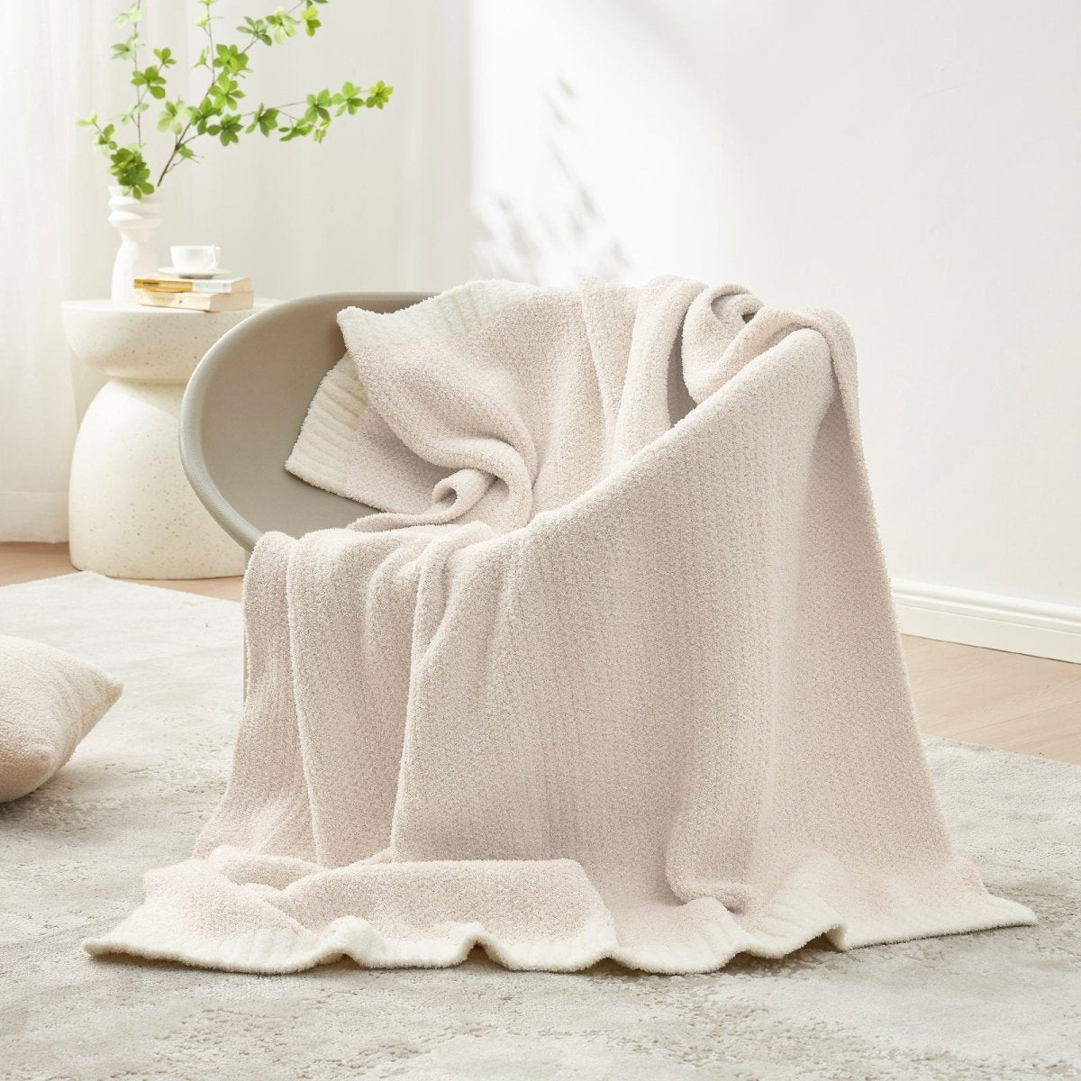 Heather Feather Yarn Throw Blanket in Ivory casually draped over a chair, creating a warm, inviting and stylish home atmosphere. #color_Ivory