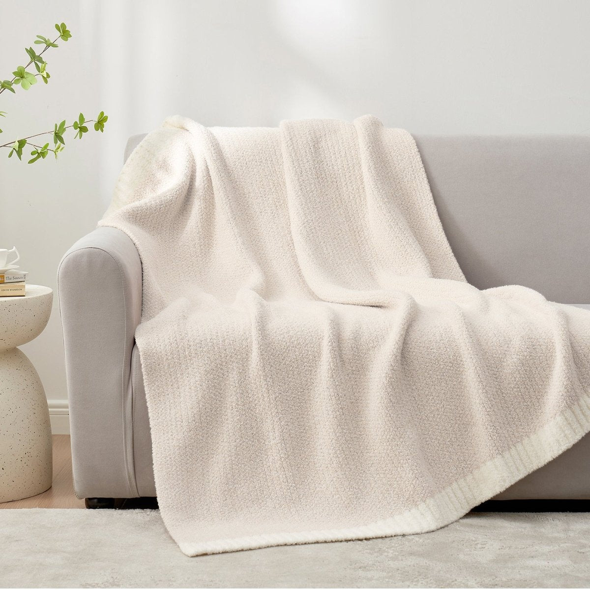 Heather Feather Yarn Throw Blanket in Ivory draped over a sofa, adding warmth, softness and a modern cozy touch to your living room. #color_Ivory