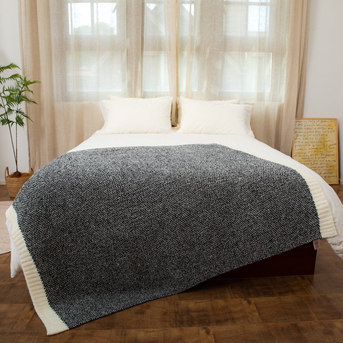 Heather Feather Yarn Throw Blanket in black styled on a bed, enhancing bedroom decor with a soft, elegant and cozy layered look. #color_Black