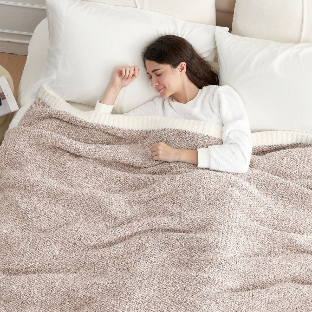 Woman lying on a bed with a Heather Feather Yarn Throw Blanket in Brown, perfect for comfort. #color_Light Brown