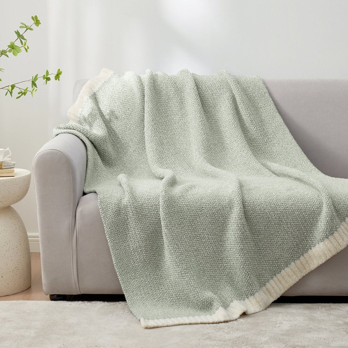 Heather Feather Yarn Throw Blanket in Sage Green draped over a sofa, adding a calm cozy feel. #color_Sage Green